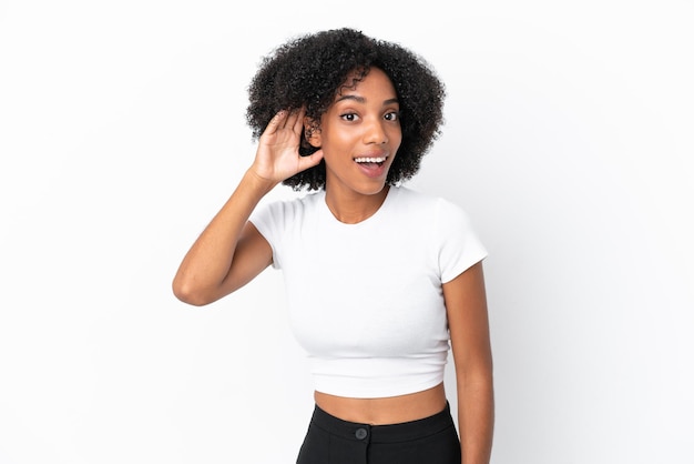 Young African American woman isolated on white background listening to something by putting hand on the ear