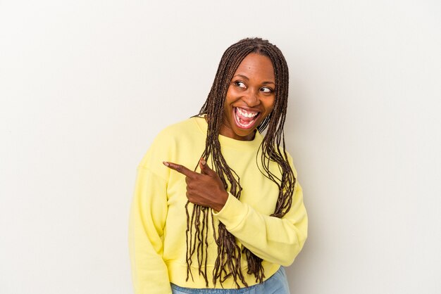 Young african american woman isolated on white background looks aside smiling, cheerful and pleasant.