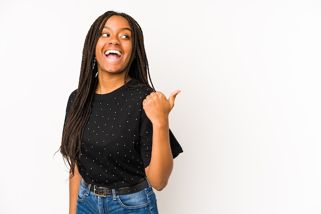 Young african american woman isolated on white background points with thumb finger away, laughing and carefree.
