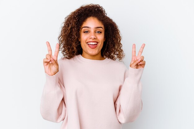 Young african american woman isolated on white background showing victory sign and smiling broadly.