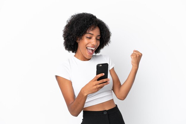 Young African American woman isolated on white background with phone in victory position