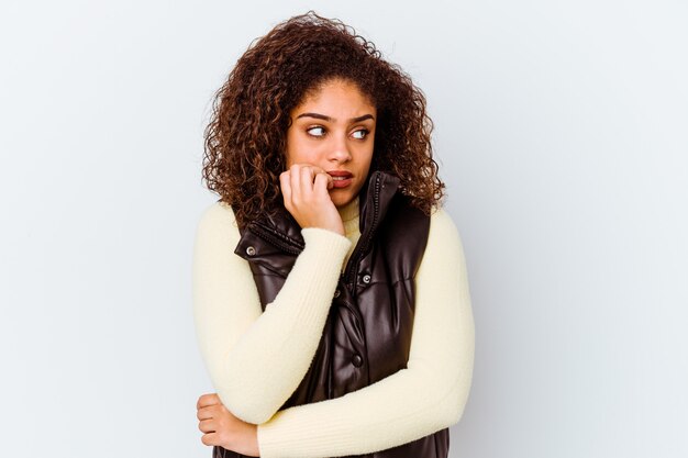 Young african american woman isolated on white wall biting fingernails, nervous and very anxious