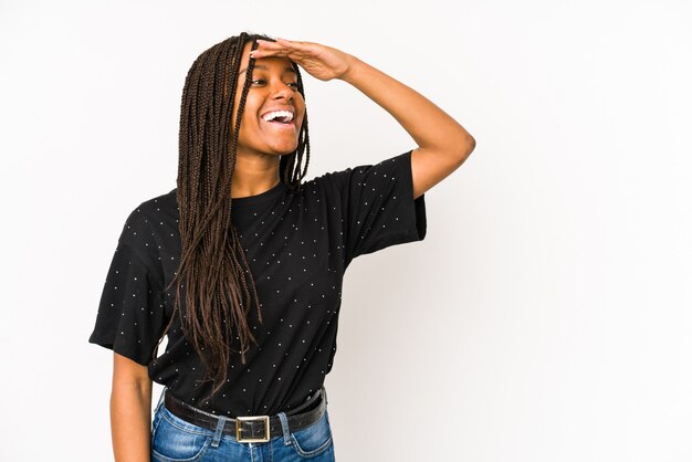 Young african american woman isolated on white wall looking far away keeping hand on forehead.