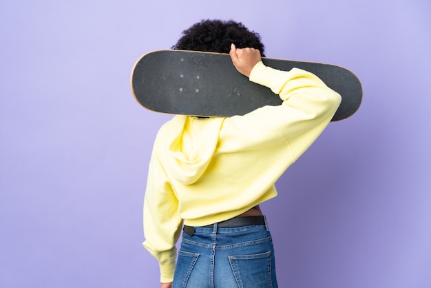 Young African American woman isolated with a skate in back position