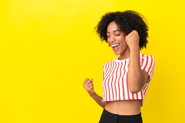 Young african american woman isolated on yellow background celebrating a victory