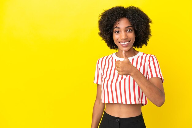 Young African American woman isolated on yellow background giving a thumbs up gesture