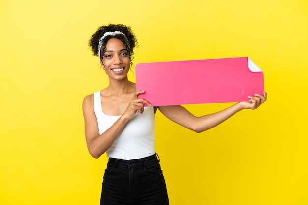 Young african american woman isolated on yellow background holding an empty placard