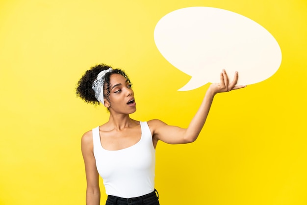 Young african american woman isolated on yellow background holding an empty speech bubble