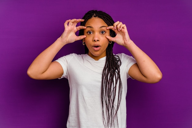 Young african american woman isolated on yellow background keeping eyes opened to find a success opportunity.