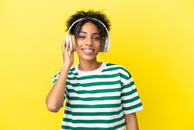 Young african american woman isolated on yellow background listening music