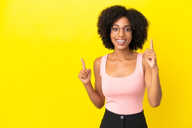 Young African American woman isolated on yellow background pointing up a great idea