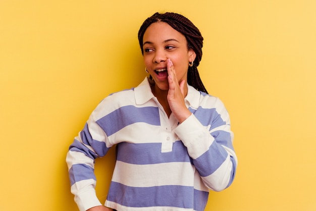 Young african american woman isolated on yellow background shouting excited to front.