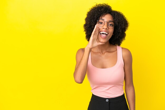 Young African American woman isolated on yellow background shouting with mouth wide open