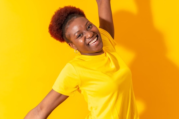 Young african american woman isolated on a yellow background smiling and dancing studio shoot