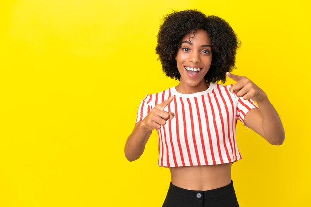 Young African American woman isolated on yellow background surprised and pointing front