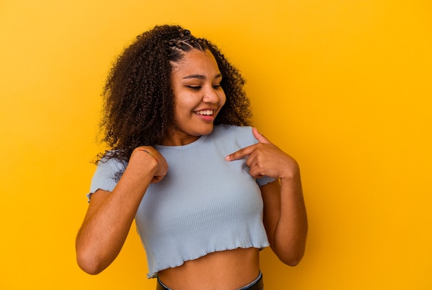 노란색 배경에 고립 된 젊은 아프리카 계 미국인 여자 광범위 하 게 웃 고 손가락으로 가리키는 놀 랐 다.