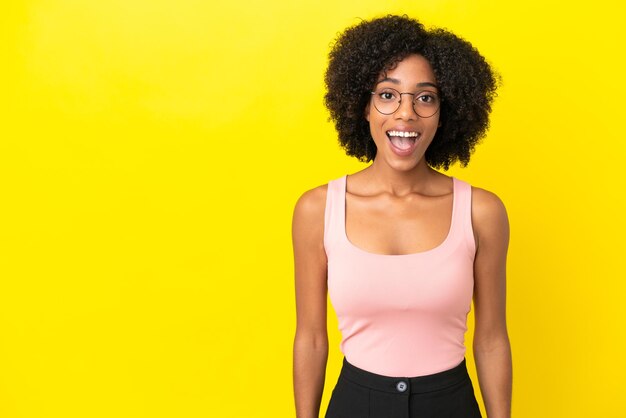 Young African American woman isolated on yellow background with surprise facial expression