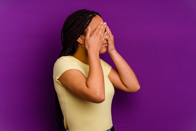 Young african american woman isolated on yellow background Young african american woman isolated on yellow background afraid covering eyes with hands.