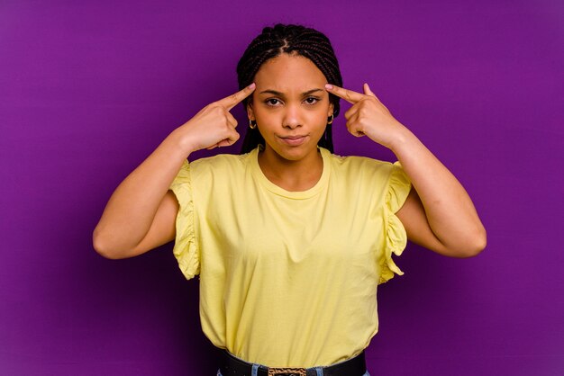 Young african american woman isolated on yellow background Young african american woman isolated on yellow background focused on a task, keeping forefingers pointing head.