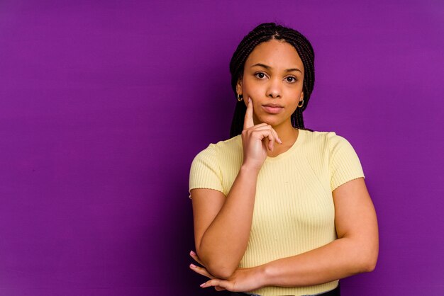 Young african american woman isolated on yellow background Young african american woman isolated on yellow background looking sideways with doubtful and skeptical expression.