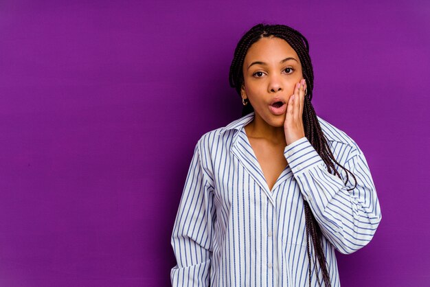 Young african american woman isolated on yellow  shouts loud, keeps eyes opened and hands tense.