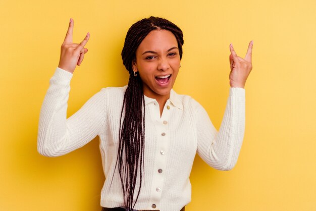 Young african american woman isolated on yellow showing a horns gesture as a revolution concept.