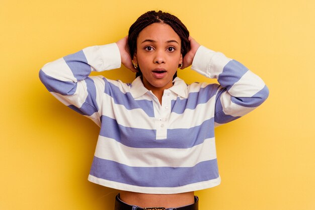 Young african american woman isolated on yellow wall covering ears with hands trying not to hear too loud sound.