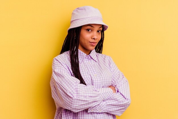 Young african american woman isolated on yellow wall unhappy looking with sarcastic expression.