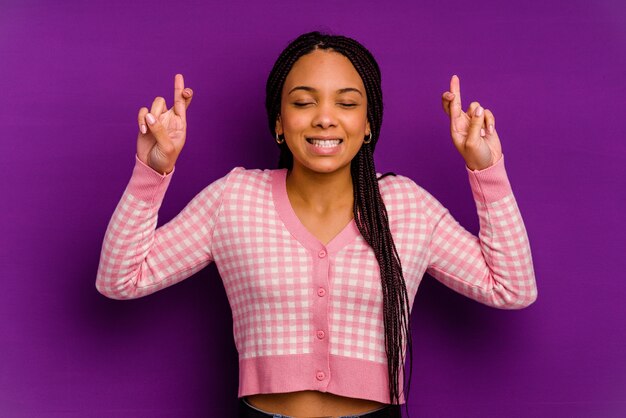 Young african american woman isolated on yellow wall Young african american woman isolated on yellow wall crossing fingers for having luck