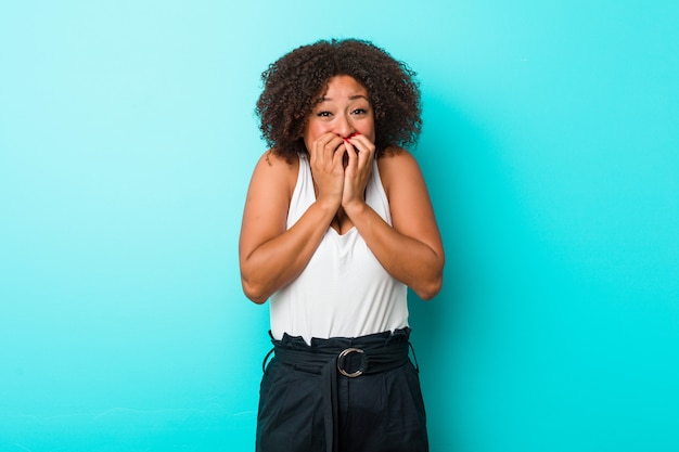 Young african american woman laughing about something, covering mouth with hands