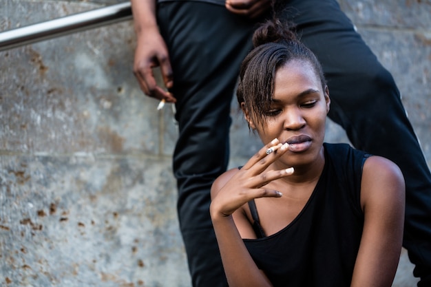 若いアフリカ系アメリカ人女性と男のcitで屋外喫煙