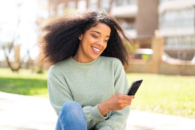 Young african american woman at outdoors using mobile phone