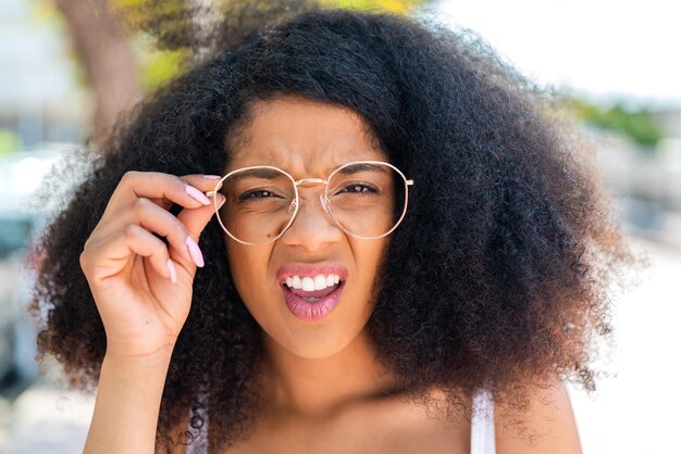 Photo young african american woman at outdoors with glasses and frustrated expression