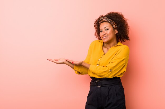 手のひらにコピースペースを保持しているピンクの若いアフリカ系アメリカ人女性。