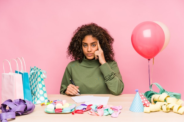 若いアフリカ系アメリカ人の女性が指で誕生日ポインティング寺院を計画し、考えて、タスクに焦点を当てた。