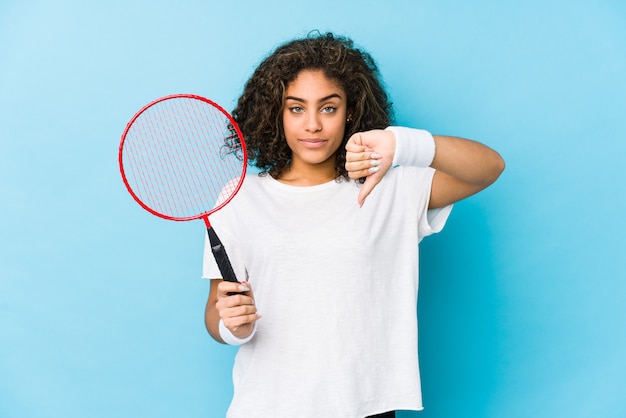 Young african american woman playing badminton showing a dislike gesture, thumbs down. Disagreement concept.