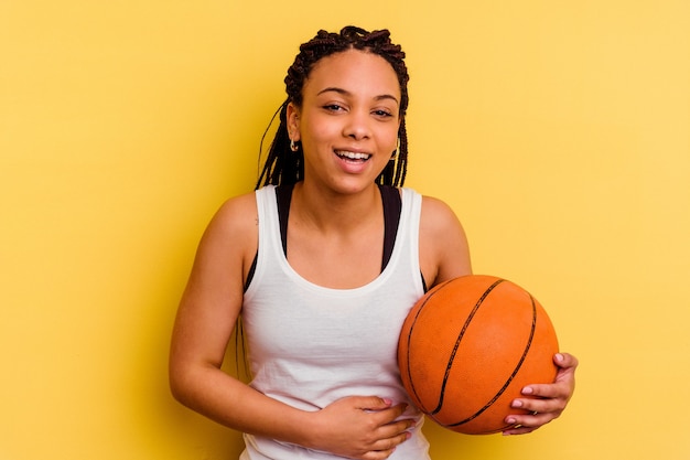 Young african american woman playing basketball   laughing and having fun.