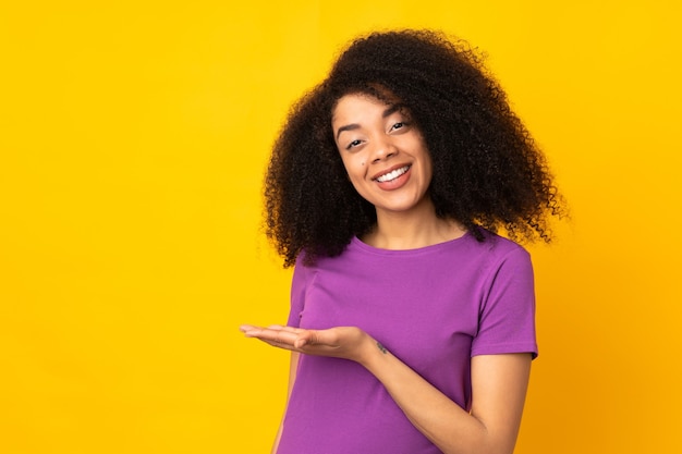 Молодая афро-американская женщина, представляющая идею, улыбаясь в сторону