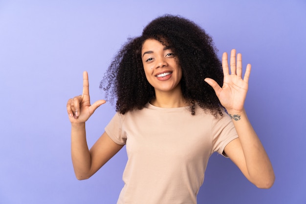 Young african american woman on purple wall counting seven with fingers