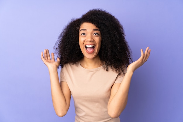 Young african american woman on purple wall with surprised facial expression