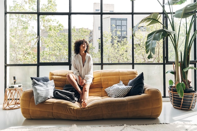 Foto giovane donna afroamericana che si rilassa e prende il sole sul sofà nello spazio della copia domestica del soppalco