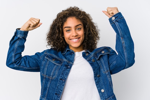 Young african american woman showing strength gesture with arms, symbol of feminine power