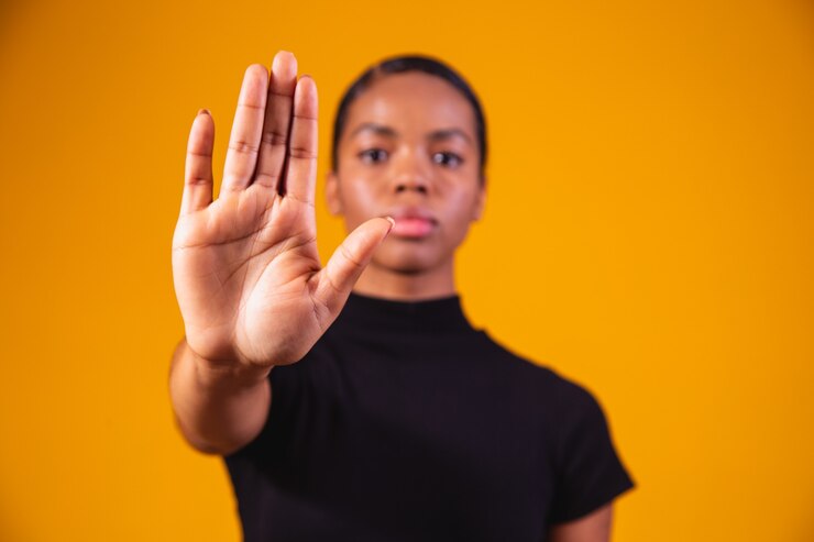 Young African American woman shown hand on sign for them to stop with racial prejudice.