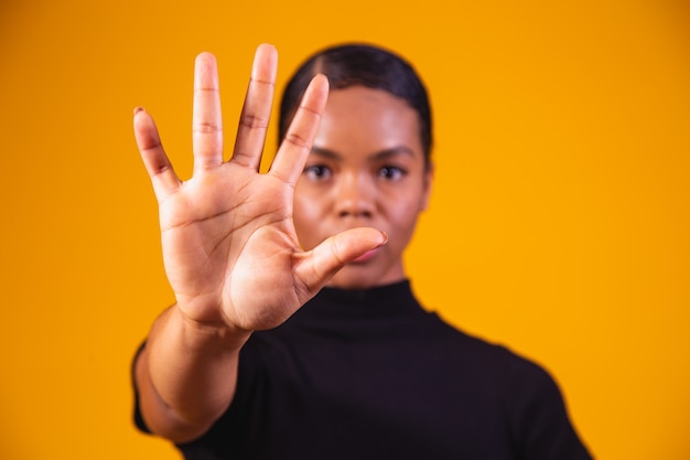 Young African American woman shown hand on sign for them to stop with racial prejudice.