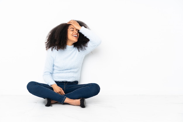 Young african american woman sitting on the floor has realized something and intending the solution