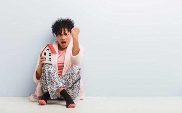 Young african american woman sitting holding a house icon