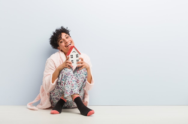 Young african american woman sitting holding a house icon