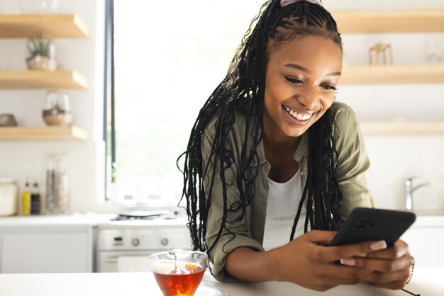 A young African American woman smiles while using her smartphone