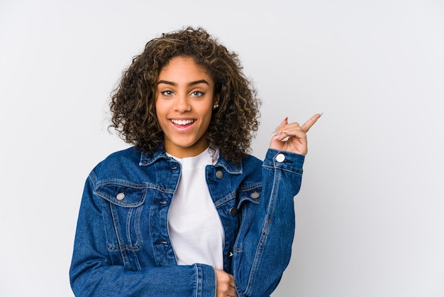 Young african american woman smiling cheerfully pointing with forefinger away.