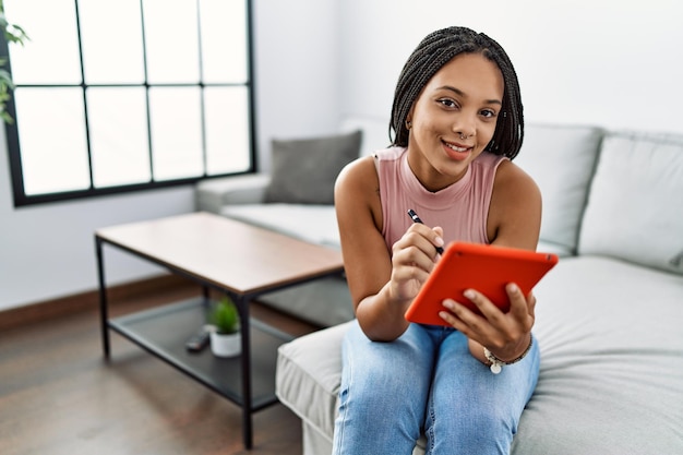 Photo young african american woman smiling confident using touchpad at home